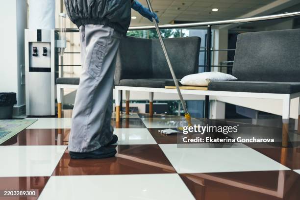janitorial work mopping checkerboard flooring in lobby area - impresa di pulizie foto e immagini stock