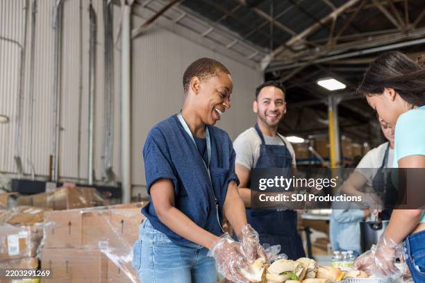 volunteers serving food at a community food bank - banco alimentar imagens e fotografias de stock