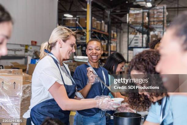 volunteers serving food at a charity soup kitchen - recolha-de-alimentos imagens e fotografias de stock