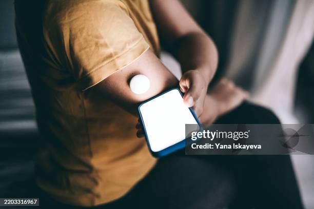 an unrecognizable person using the glucose monitor, checking the mobile app for more blood sugar level data - biosensor fotografías e imágenes de stock