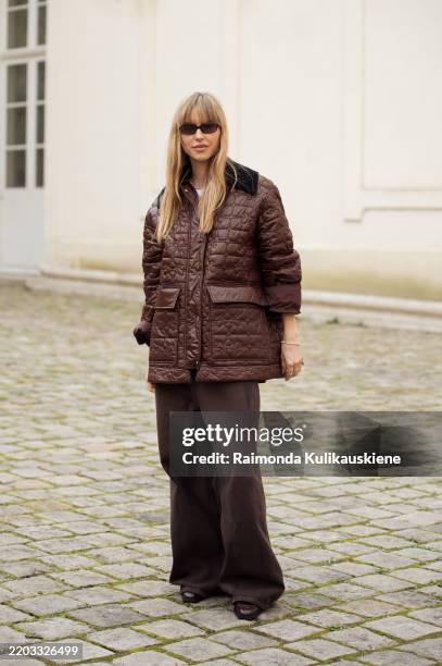 Pernille Teisbaek wears wide brown pants, brown leather jacket and sunglasses outside the Ganni fashion show during the Womenswear Fall/Winter...