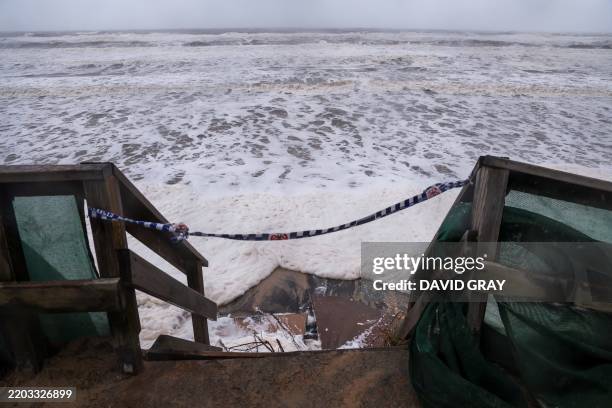Waves break onto a stairway along the footpath along Main Beach located on the Gold Coast on March 8, 2025. Cyclone Alfred weakened into a tropical...