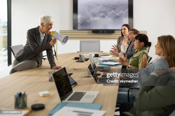 wütende senior-ceo, die ihre kollegen bei einem meeting schikaniert. - kommunikationsproblem stock-fotos und bilder
