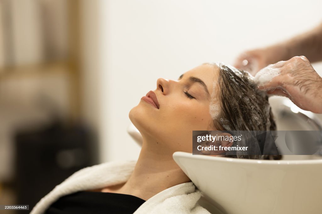 Frau, die sich beim Friseur die Haare waschen lässt