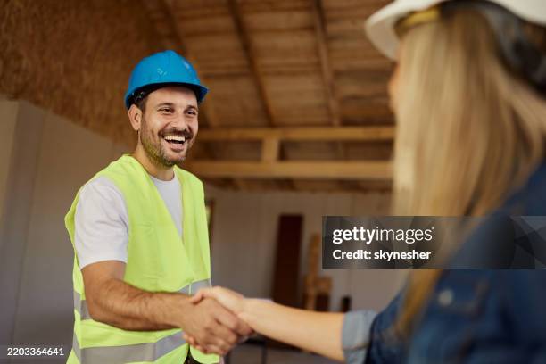 happy worker greeting female inspector at construction site. - handshake site stock pictures, royalty-free photos & images
