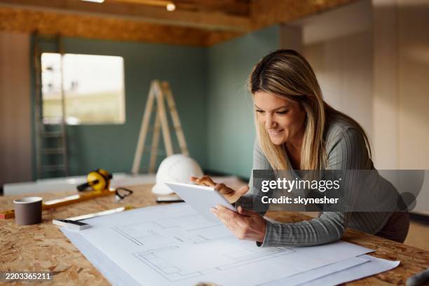 female architect surfing the internet on digital tablet at construction site. - architect stock pictures, royalty-free photos & images
