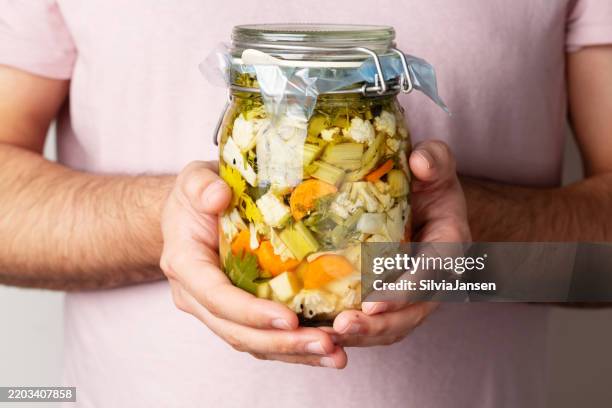 fermenting food: hands hold a jar with homemade mixed pickles - i was turning into a vegetable stock pictures, royalty-free photos & images