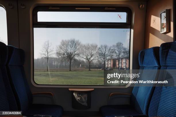 a train carriage featuring blue-patterned seats and a large window - train window reflection stock pictures, royalty-free photos & images