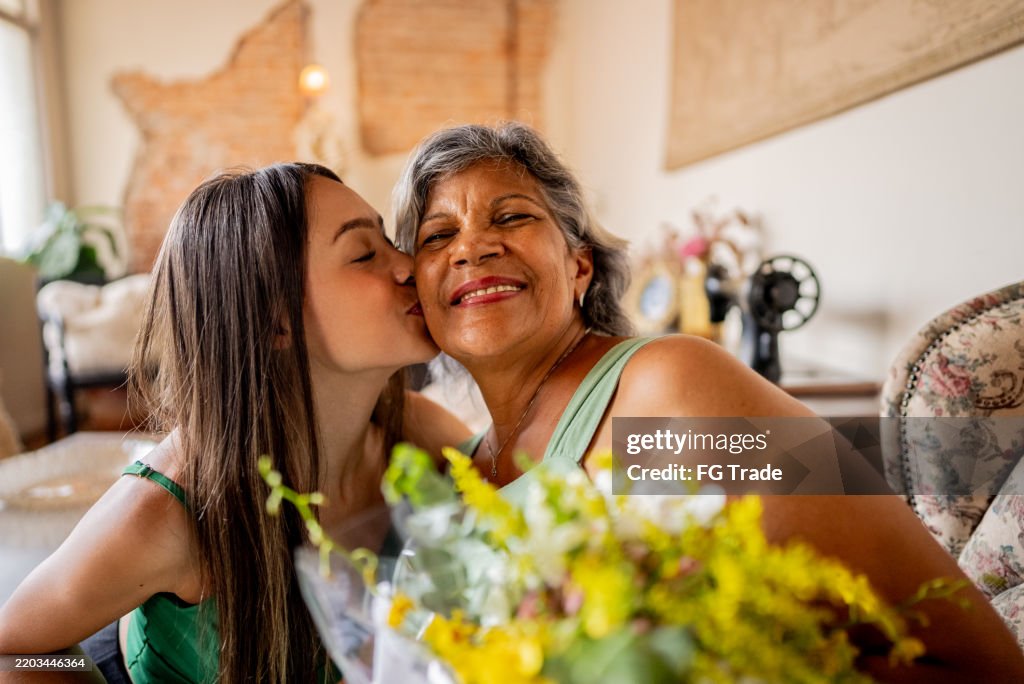 Junge Frau, die ihrer Mutter zu Hause Blumen schenkt