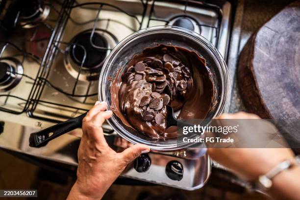 primo piano della donna che scioglie il cioccolato a casa - sciogliere foto e immagini stock