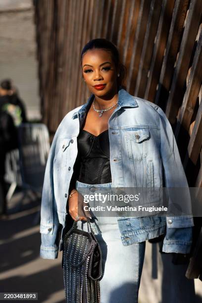 Guest wears a diamond necklace, a black corset, a denim high waist skirt, diamond earrings, a denim jacket and a black mini Falabella Stella...