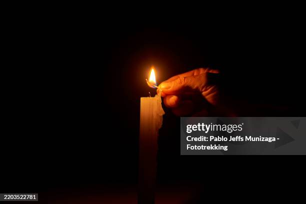 hand lighting a candle with a match in the dark - apagão imagens e fotografias de stock