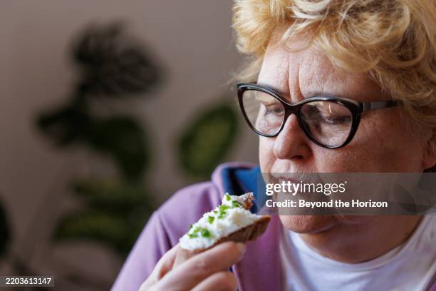 woman eating slice of bread with homemade kefir cheese and fresh spring onions - só uma mulher idosa imagens e fotografias de stock