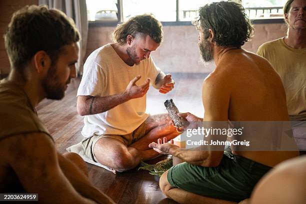 man sitting cross legged on floor inhaling smoke during smudge stick ceremony - sage stock pictures, royalty-free photos & images