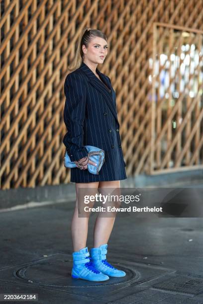Franziska Nazarenus wears dark blonde slick bag hair with high ponytail, black white pinstripe double breasted blazer jacket, light blue Stella...