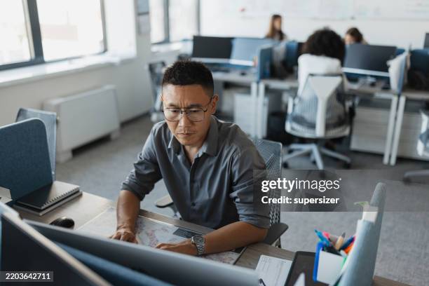 concentrated man working at computer in bright office - person of color stock pictures, royalty-free photos & images