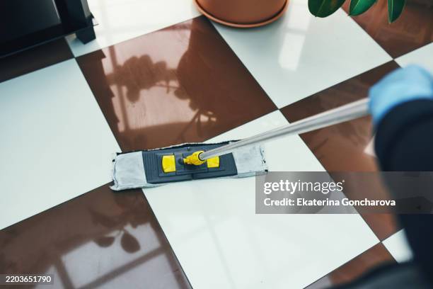 person cleaning tiled floor with mop in indoor environment - facilité photos et images de collection