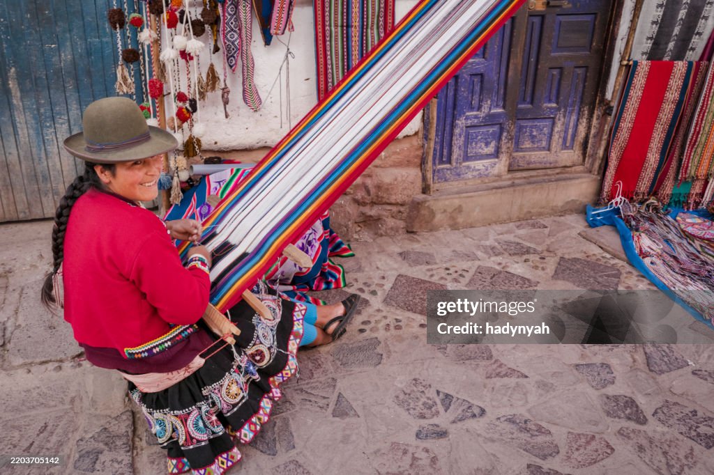 Peruvian woman weaving and selling souvenirs in Pisac, Urubamba Valley