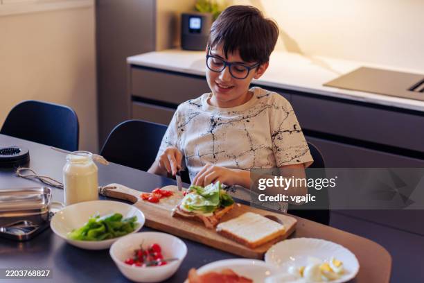 10-year-old boy making a sandwich and packing school lunch in a home kitchen - making a sandwich stock pictures, royalty-free photos & images