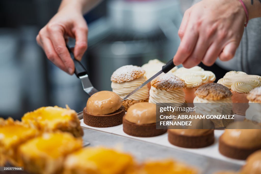 Der Konditor positioniert Windbeutel und Torten sorgfältig und unterstreicht die kulinarische Handwerkskunst mit zarten, präzisen Arrangements auf dekorativen Tabletts