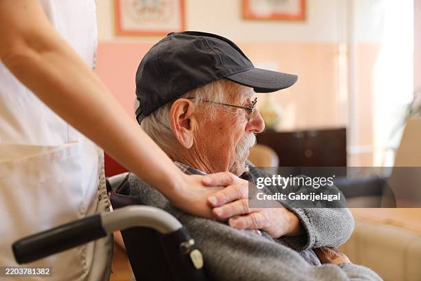 elderly man in a wheelchair talking to a nurse at a nursing home - vårdhem bildbanksfoton och bilder