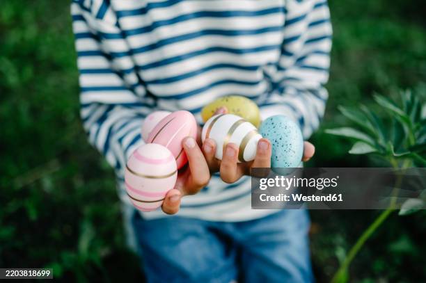 hands of boy holding colorful patterned easter eggs - easter egg hunt stock pictures, royalty-free photos & images