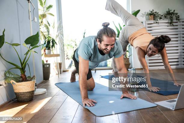 happy man and woman practicing yoga on mats at home - exercise room stock pictures, royalty-free photos & images