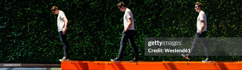 Man with hands in pockets walking on bench