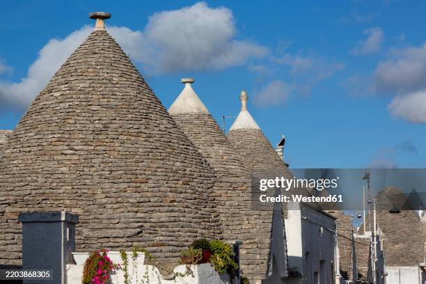 traditional trulli houses in alberobello, apulia, italy under a blue sky - trullo house stock pictures, royalty-free photos & images