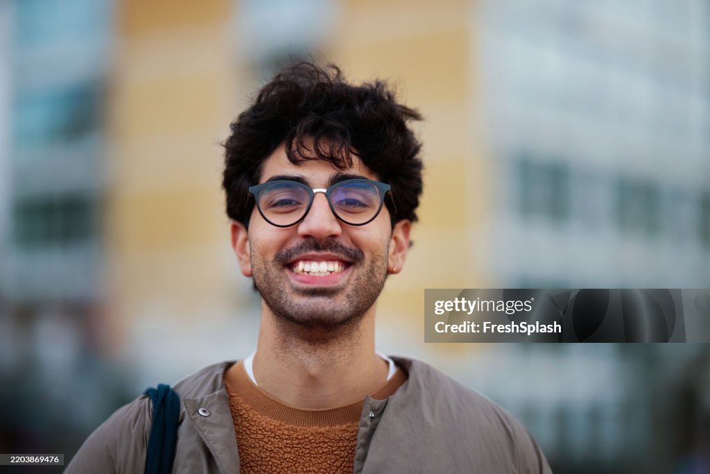 Smiling Young Man Wearing Glasses Against Urban City Background