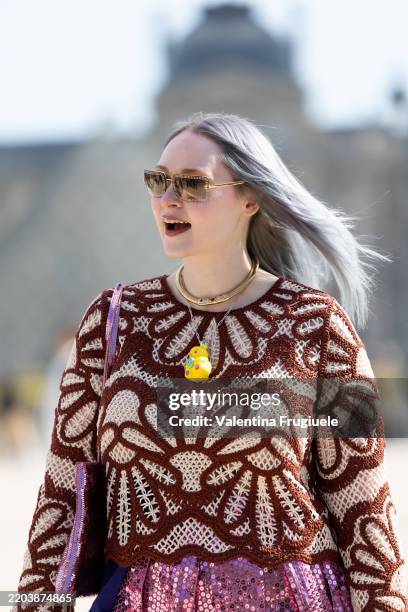 Guest wears grey sunglasses, a yellow suck-shaped necklace, a pink sequins bag, a brown and beige knitted cropped long sleeved top and a pink...