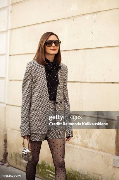 Olivia Palermo wears black tights, black and white checkered shorts and matching jacker, black top with white polka dots, sunglasses and silver...