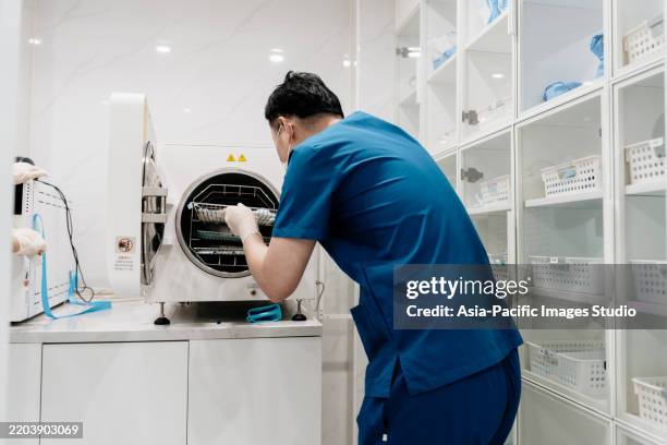 rear view of dentist assistant sterilizing the equipment used in the dental clinic. - medische apparatuur stockfoto's en -beelden