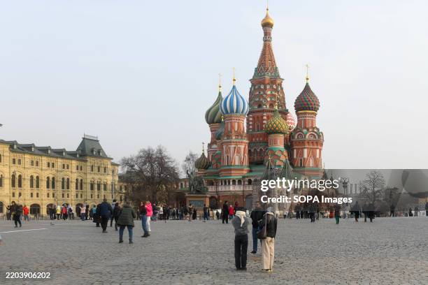 People stroll on red Square at the Kremlin near the Middle Shopping malls and the Cathedral of the Intercession of the Blessed Virgin Mary.