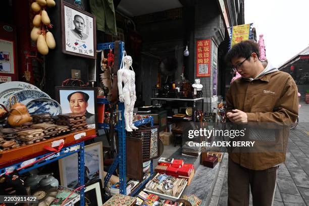 Portraits of communist leader Mao Zedong and China's former president of the Republic of China Sun Yat-sen are seen as a man browses through items on...