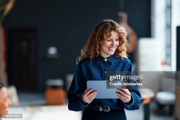 lächelnde frau, die tablet im modernen geschäftsbüro hält - initiative stock-fotos und bilder