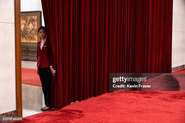 An usher holds a curtain open in the hallway during the second plenary session of the National Peoples Congress, or NPC, at the Great Hall of the...