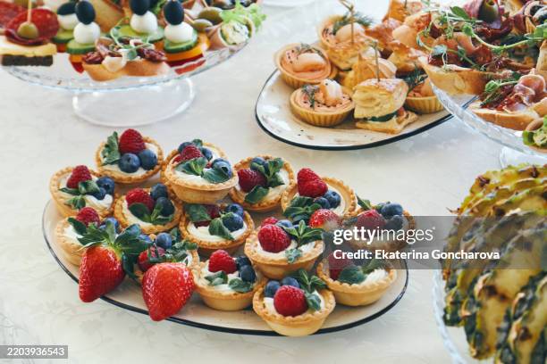assorted desserts and savory finger foods on elegant white table setting - sweet buffet stock pictures, royalty-free photos & images