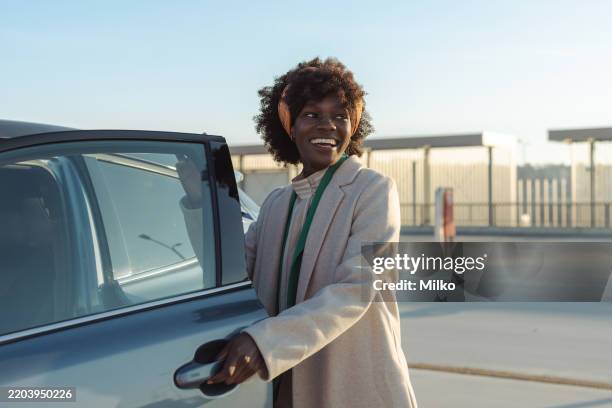 smiling woman opening her car door on a sunny day outdoors - car door stock pictures, royalty-free photos & images