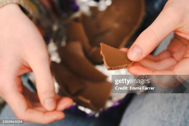 close up hands opening a chocolate egg - schokolade stock-fotos und bilder