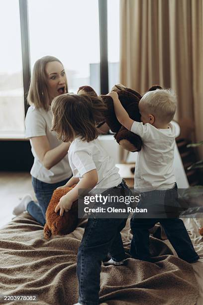 shocked mother playing with her children on the bed. - teddy bear tshirt stock pictures, royalty-free photos & images