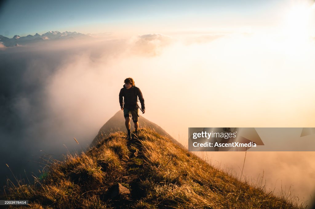 Hiker explores trail on mountain ridge at sunrise