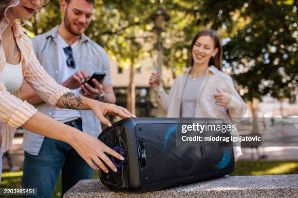 freunde genießen musik und sonnenschein im park - bluetooth stock-fotos und bilder