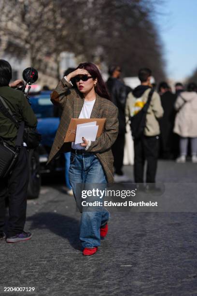 Guest wears black sunglasses, gold earrings, white t-shirt, light brown pattern/print oversized blazer jacket, navy blue washed baggy denim jean...