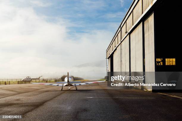 ultralight aircraft parked on airfield near hangar in morning mist - hangar fotografías e imágenes de stock