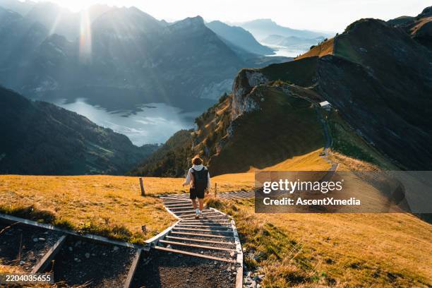 young man hikes on mountain ridge above lake - paisagem espetacular imagens e fotografias de stock