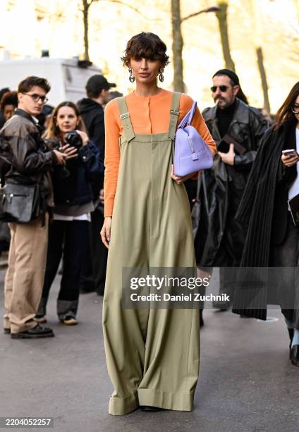 Irina Kro Eicke is seen wearing an orange top, green overalls and purple bag outside the Hermes show during the Womenswear Fall/Winter 2025/2026 as...