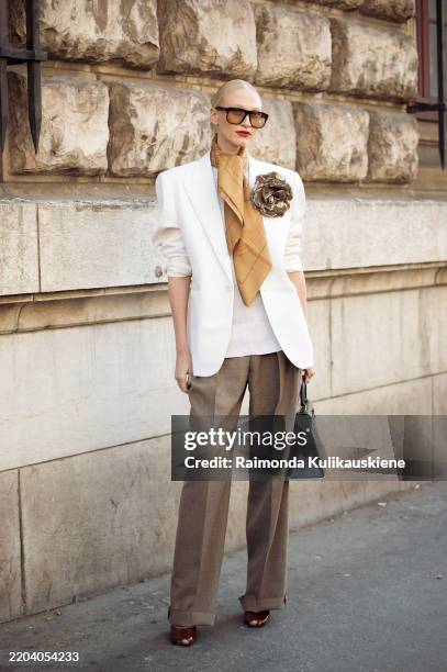Yulia Harfouch wears white blazer with golden flower, beige scarf, beige pants, sunglasses, black bag outside the Hermes fashion show during the...