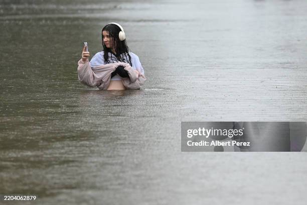Resident walks on a flooded Edmonstone Street in the suburb of Newmarket on March 09, 2025 in Brisbane, Australia. Australia's east coast is...