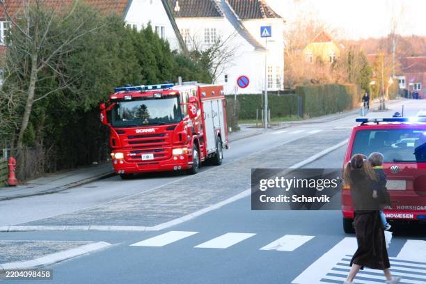 woman carrying a small child watching fire trucks respond - emergency services vehicle stock pictures, royalty-free photos & images